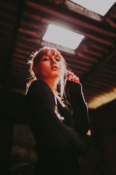 Low angle shot of a woman posing indoors with dramatic lighting and dust particles.