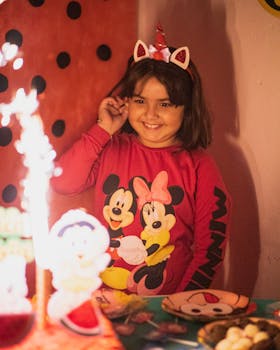 A joyful young girl celebrates her birthday with a Minnie Mouse themed party, complete with decorations and smiles.