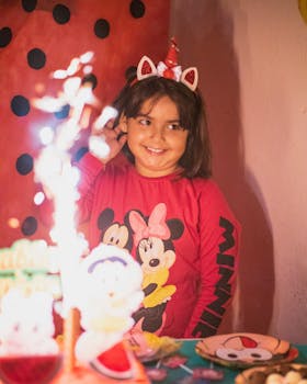 A smiling girl enjoys her birthday party with festive decorations, inside a cozy setting.