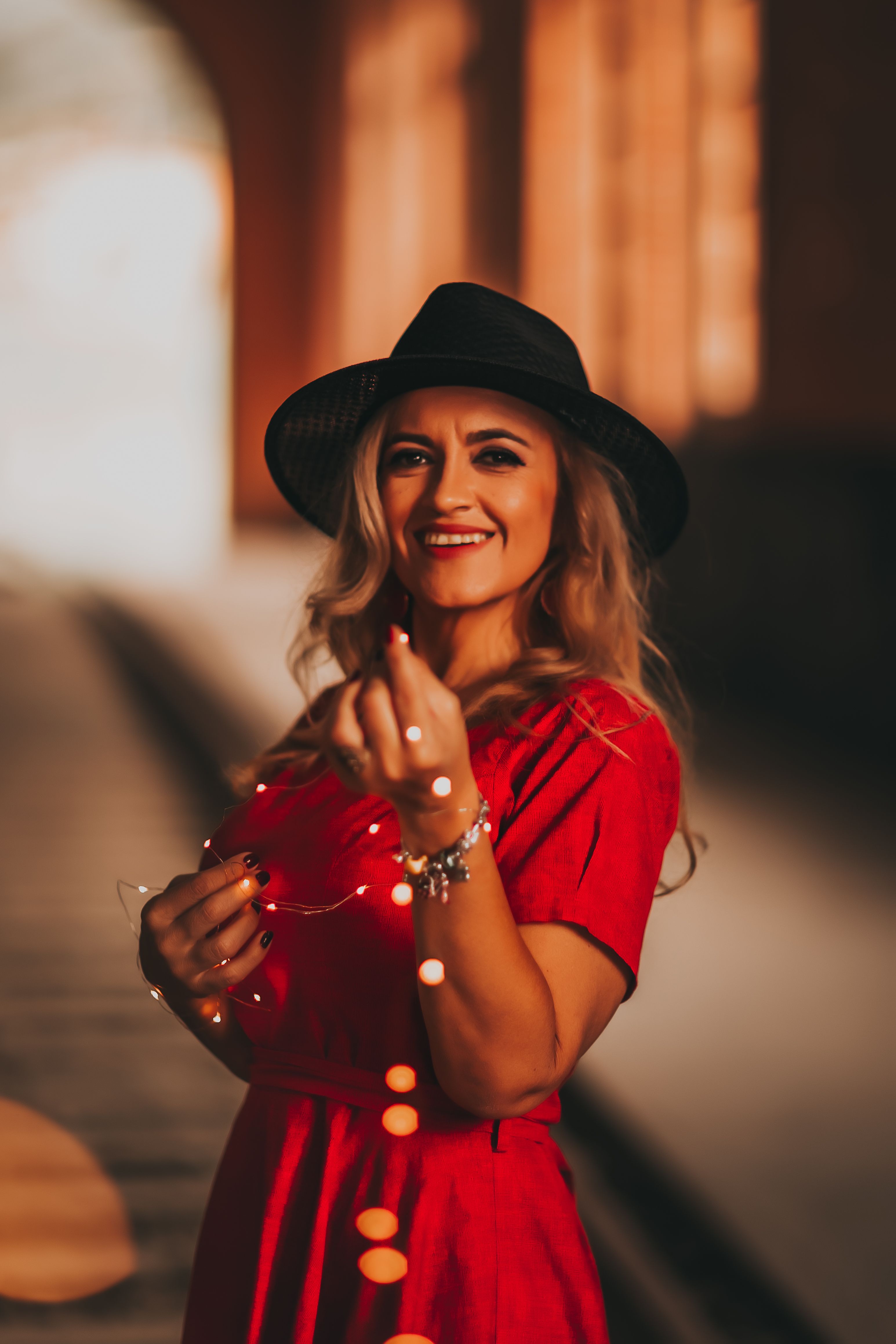 A Woman in Red Dress Wearing Black Fedora Hat while Smiling at the ...