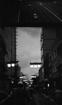 A bustling city street at night with pedestrians and streetlights in black and white.