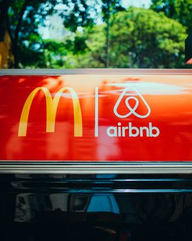 Bright sign showcasing recognizable logos on a vehicle's roof with blurred trees in the background. 13870633
