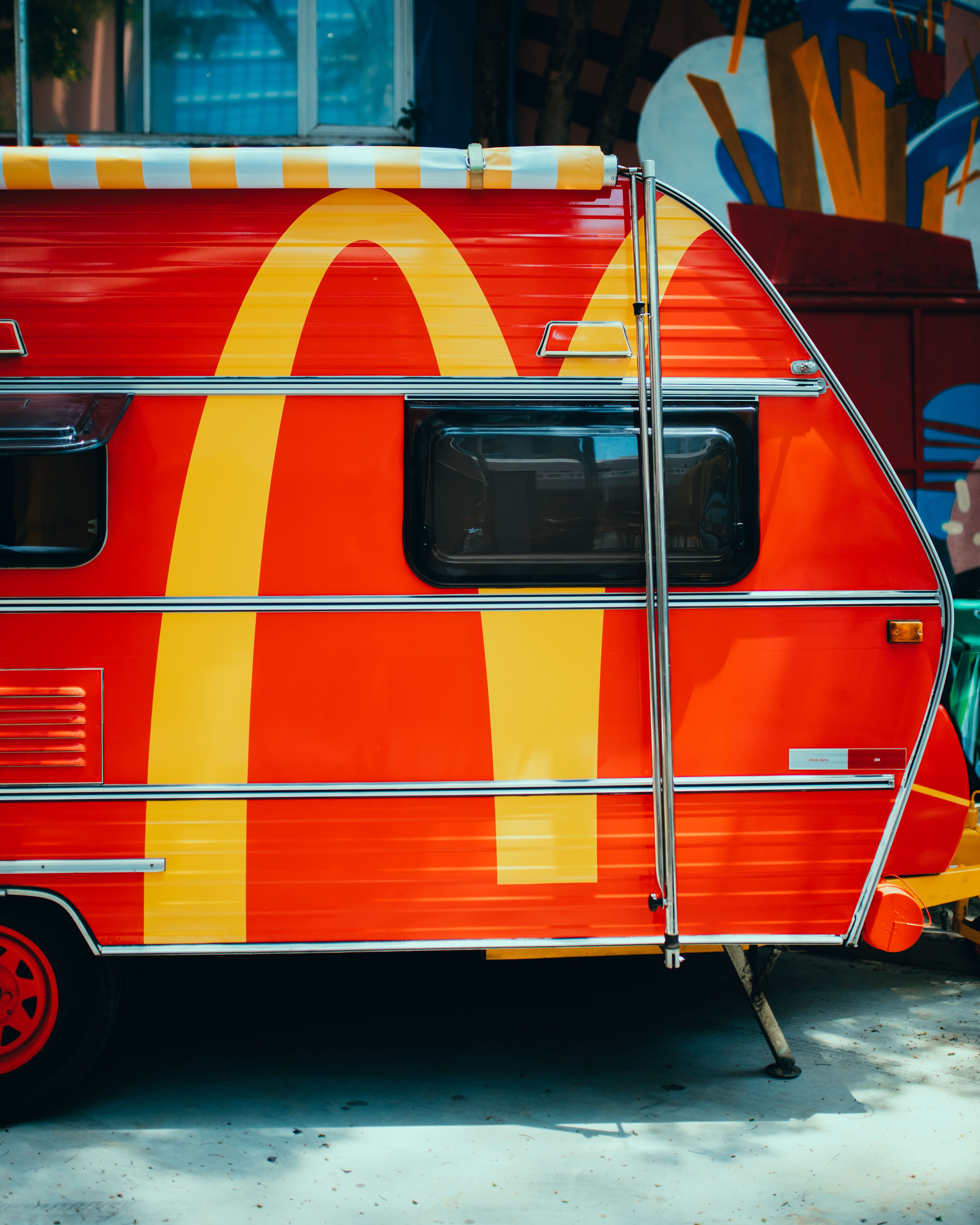 A colorful red trailer adorned with an iconic golden arch symbol, parked outdoors.