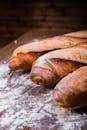 Close-up Photo of Three Baguettes on Brown Wooden Surface With White Powder