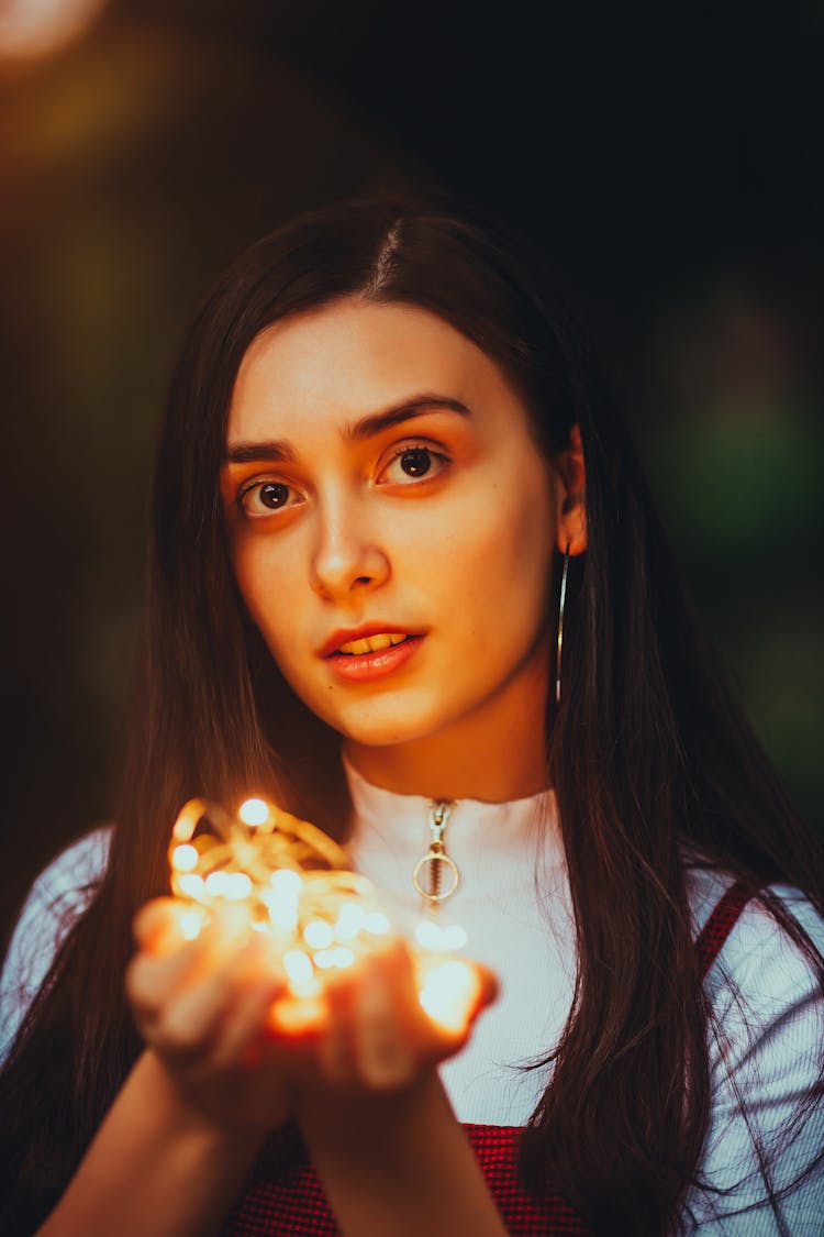 Young Brunette Woman Holding Fairy Lights In Hands 