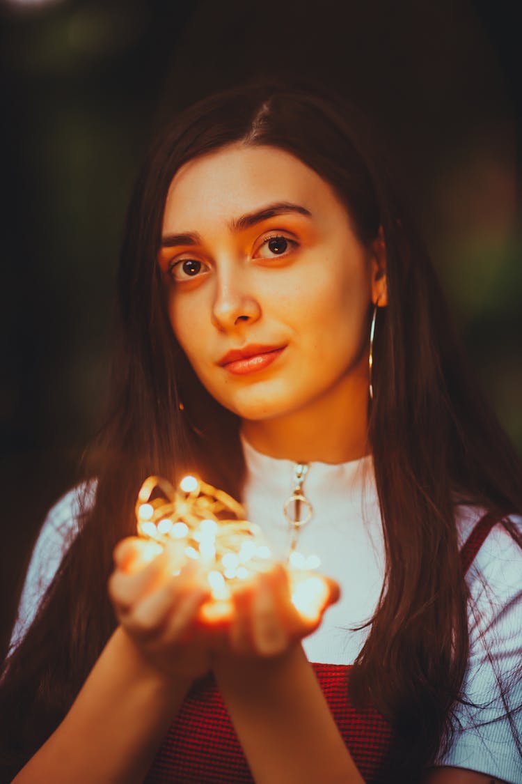 Young Brunette Woman Holding Fairy Lights In Hands 