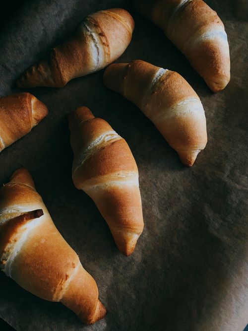 Free Golden croissants on brown parchment paper, fresh from baking. Stock Photo