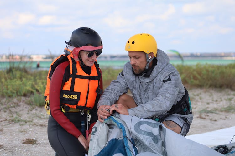 Man Teaching A Woman Unfolding A Kite