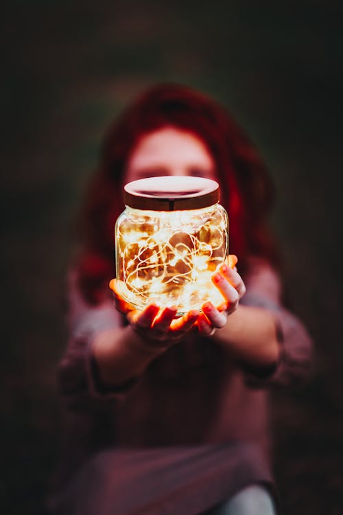 Person Holding a Glass Jar with String Lights