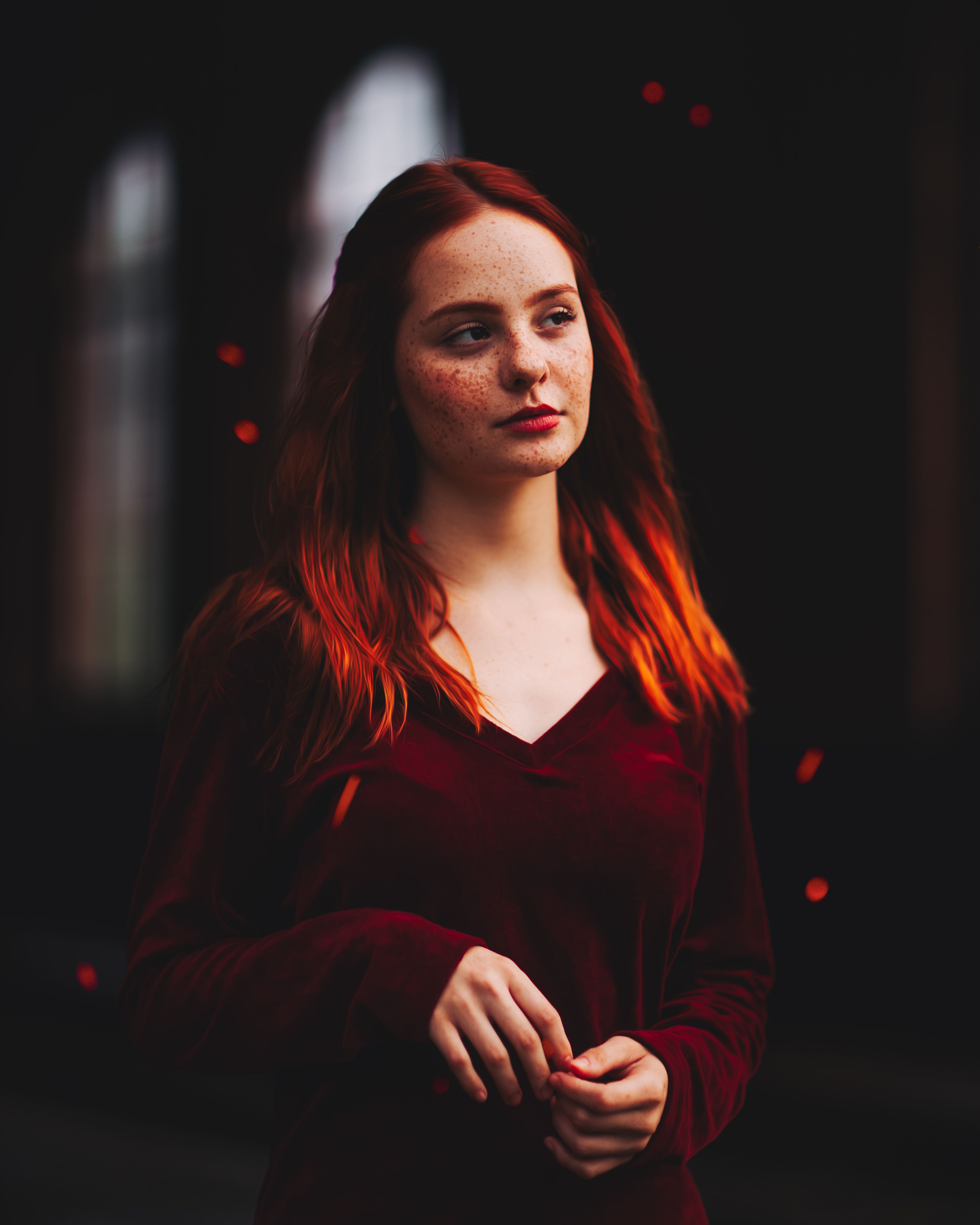 Stunning portrait of a redhead woman in a dark background, showcasing her natural freckles.