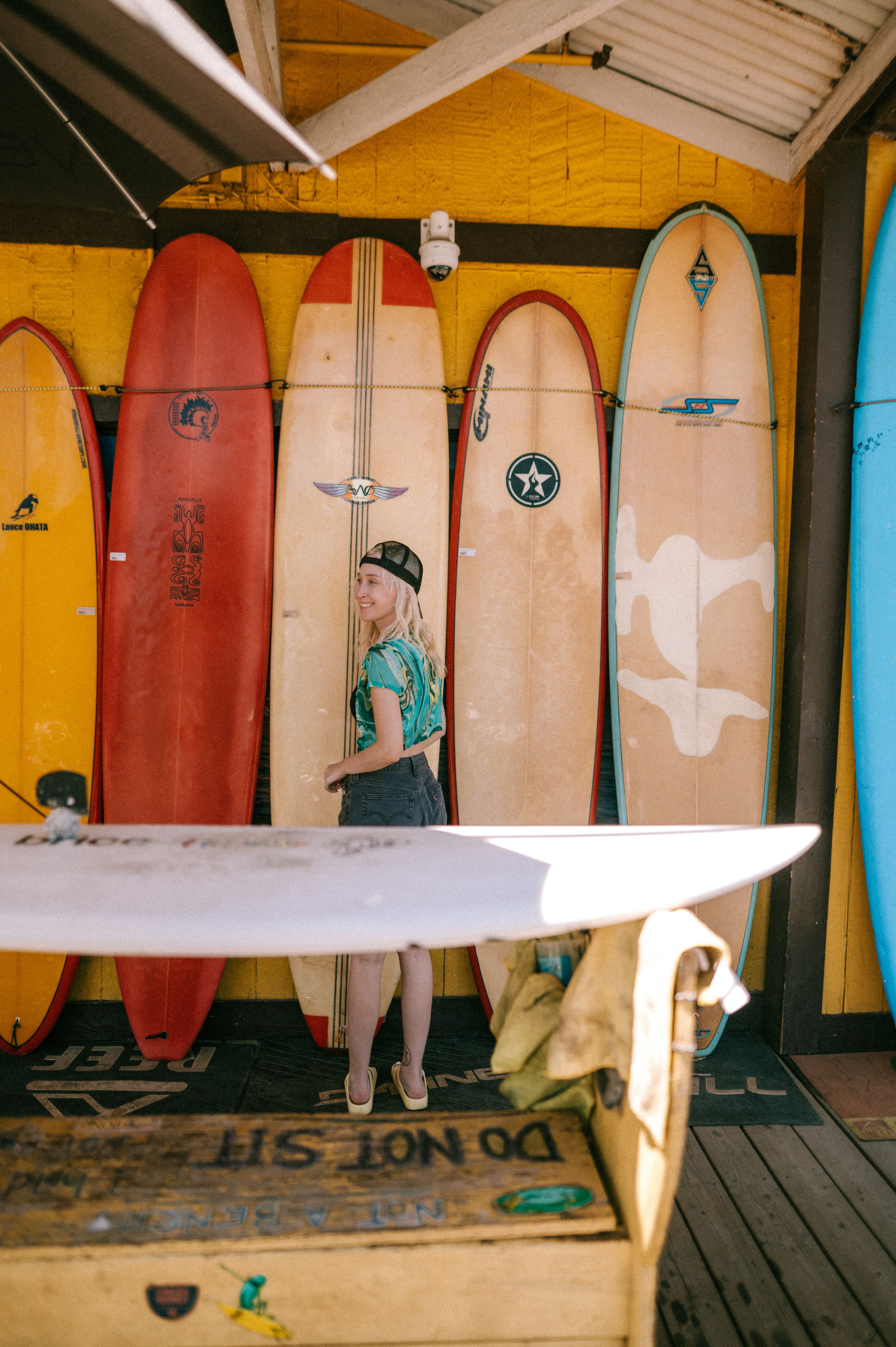 A woman admires surfboards in a vibrant surf shop. Perfect for surfing enthusiasts.