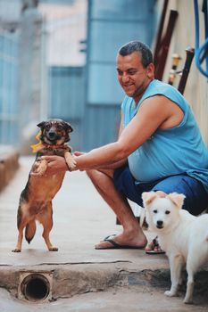A man interacts happily with two dogs outdoors, showcasing companionship and joy.