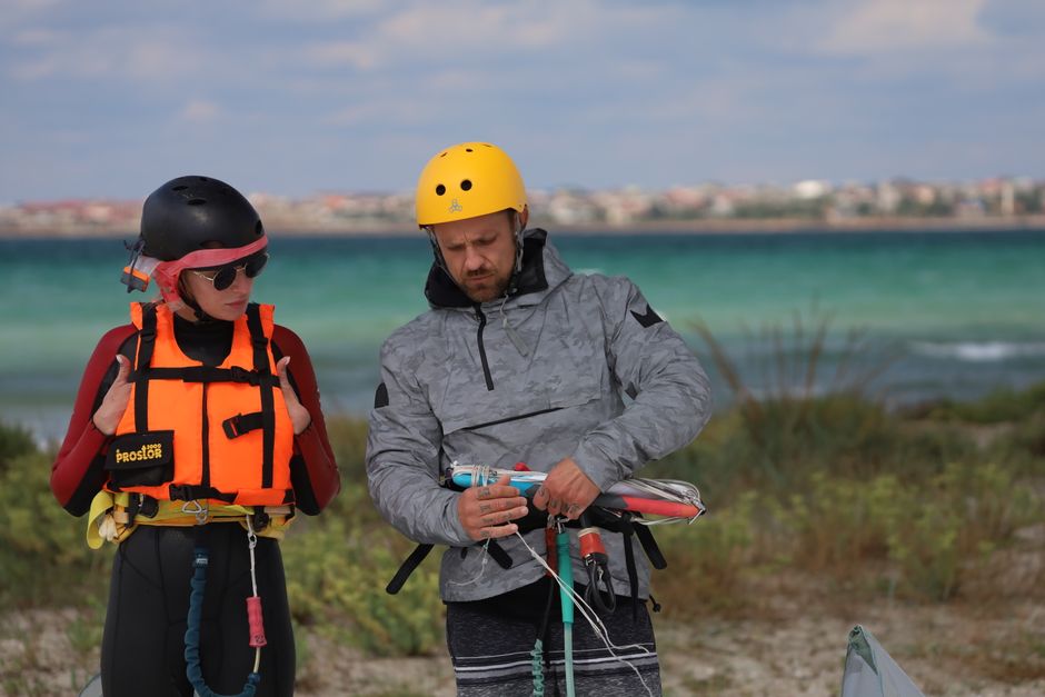 Man and woman preparing for kite surfing by the sea on a windy day.