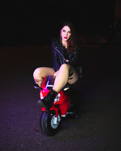 Beautiful Woman Sitting on a Red Toy Motorcycle
