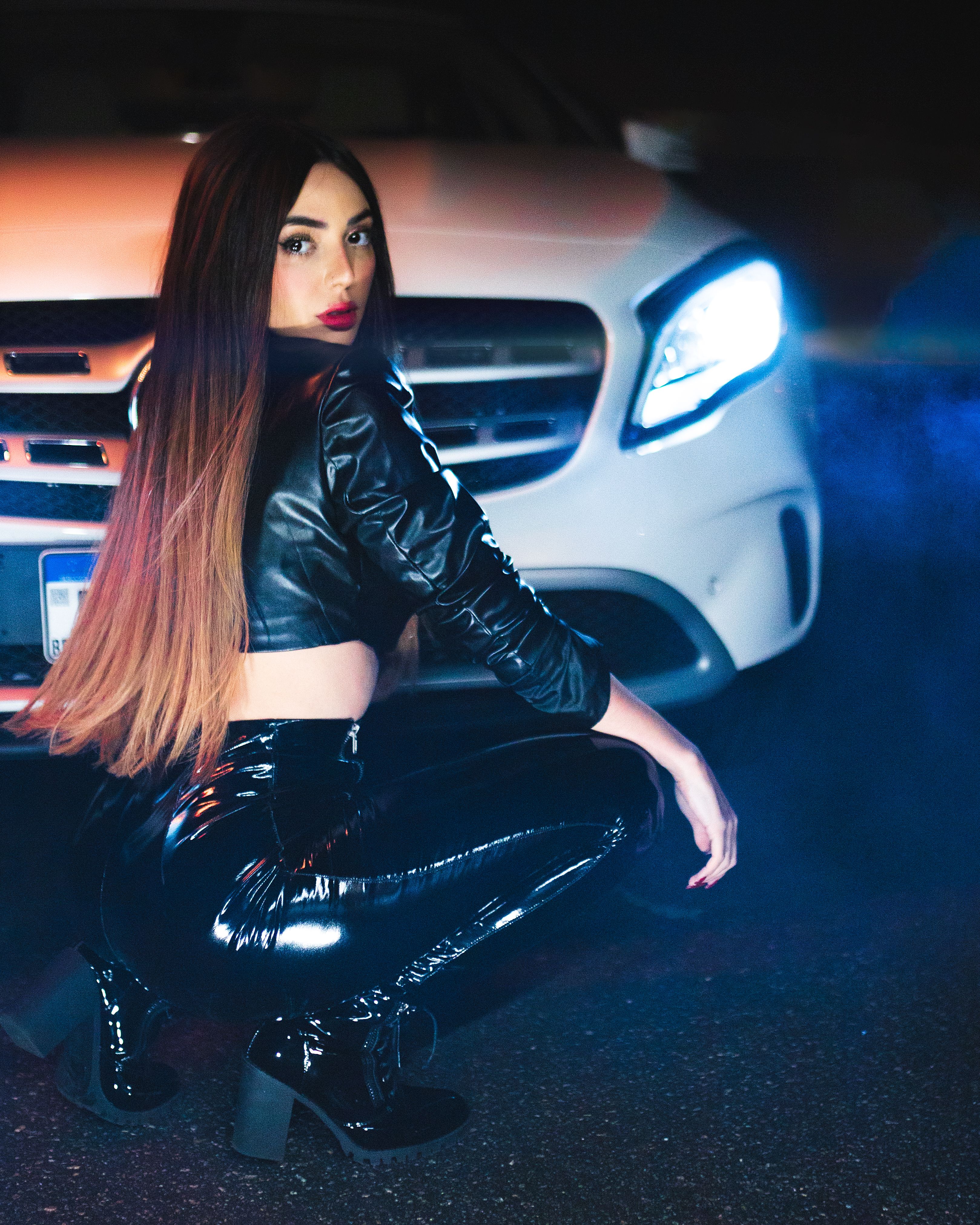 Woman Crouching in front of a Car · Free Stock Photo