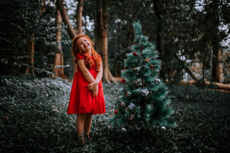 Woman in a red dress beside a decorated Christmas tree
