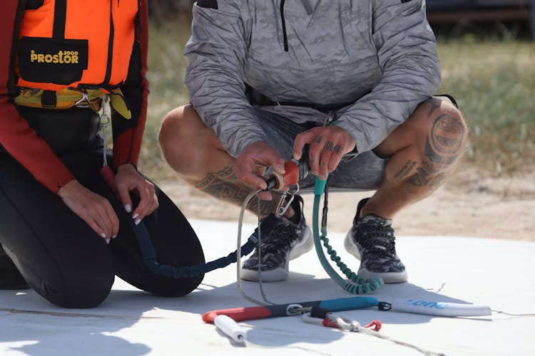 Man Preparing Woman In Uniform For Paragliding