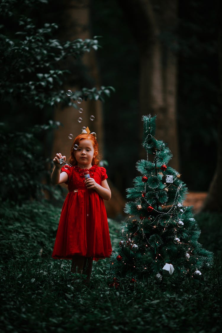 Girl Blowing Bubbles Near Christmas Tree