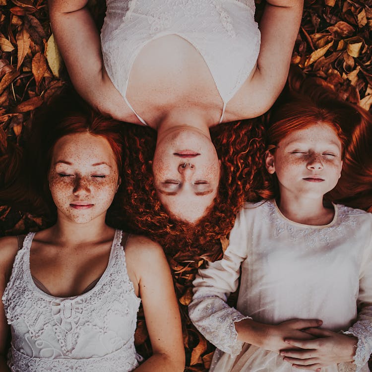 Redhead Girls Lying On Ground With Leaves