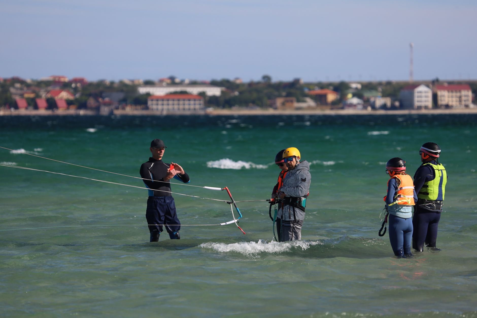 Enthusiasts learning kiteboarding with safety gear by the sea. Engaging outdoor water activity.