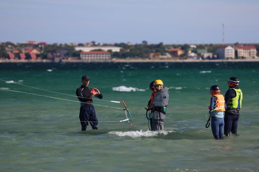 Enthusiasts learning kiteboarding with safety gear by the sea. Engaging outdoor water activity.
