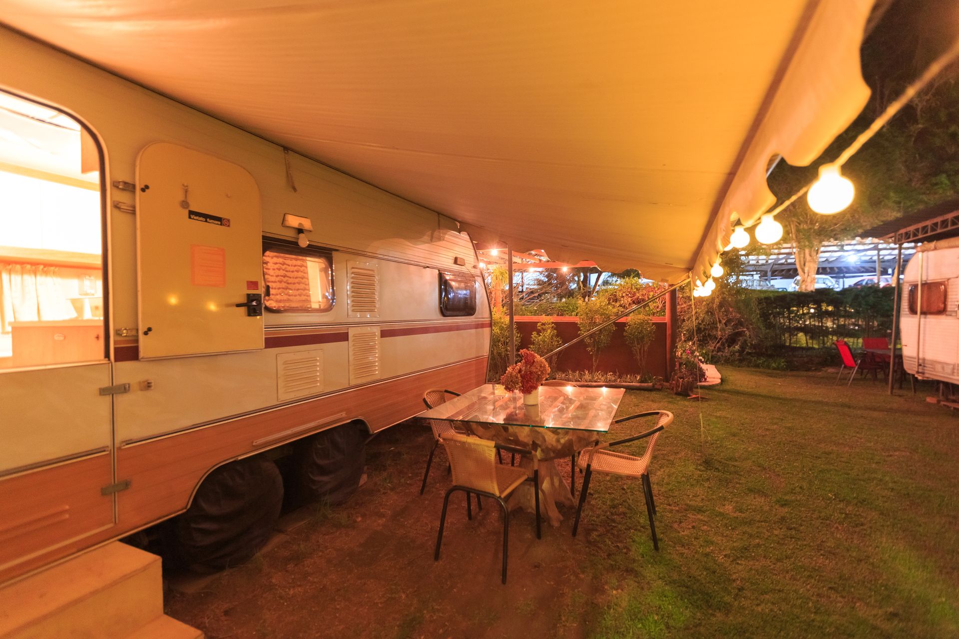 Relaxing night scene of an outdoor RV setup with ambient lighting and a dining table.