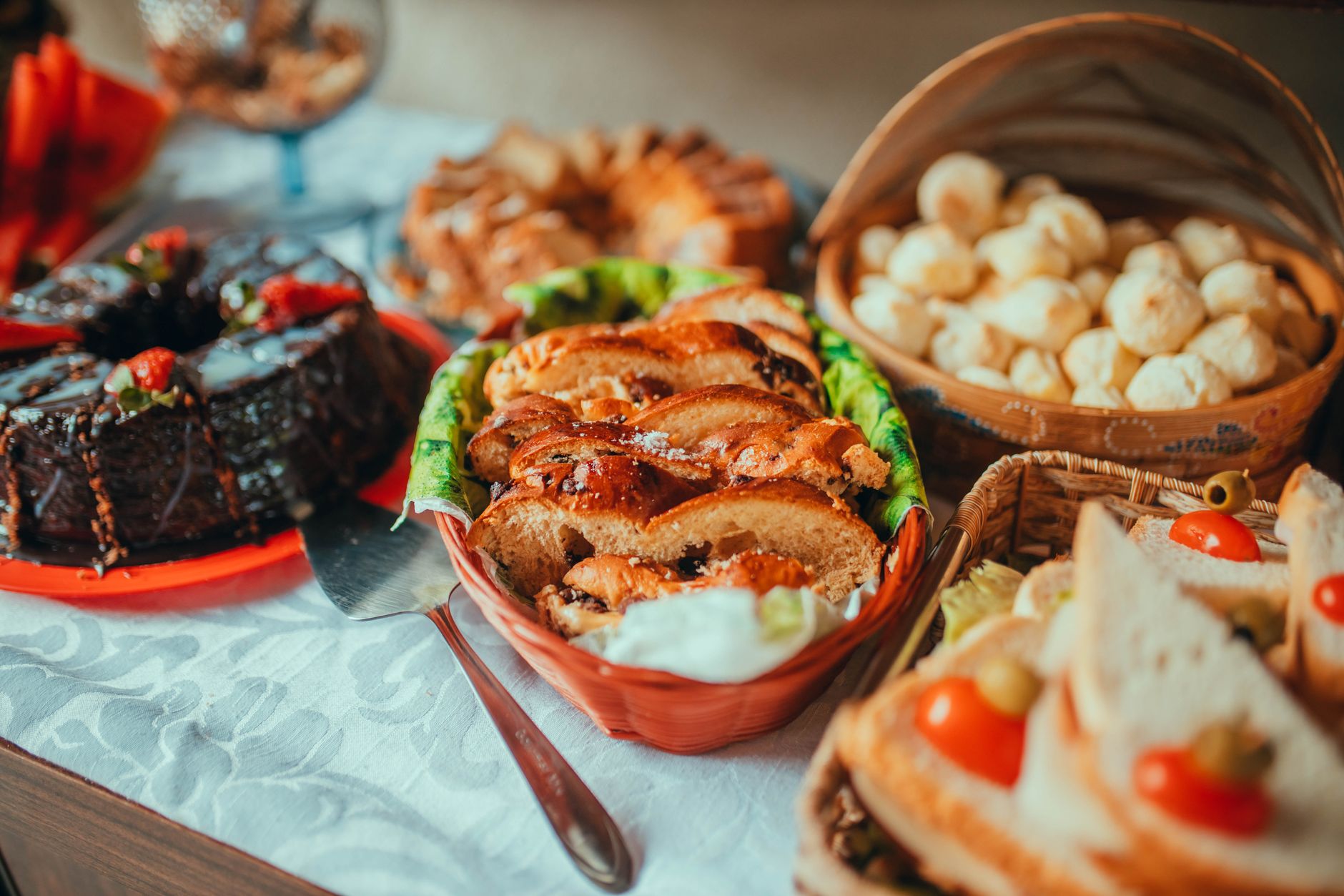 A variety of breads and cakes beautifully presented on a breakfast table with appetizing garnishes.
