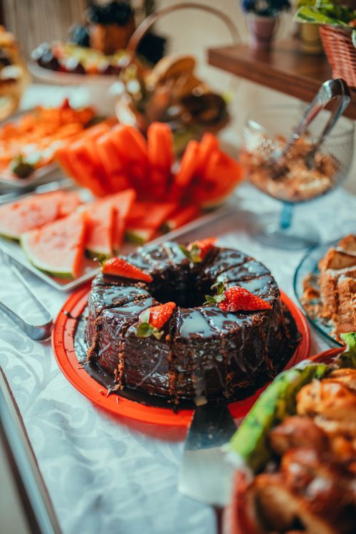 Free Delicious chocolate cake with strawberries surrounded by watermelon slices on a vibrant buffet table. Stock Photo