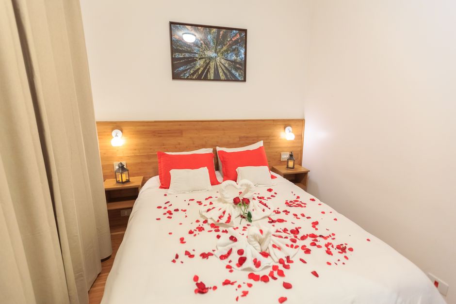 Fotomural Acogedora habitación de hotel con pétalos de rosa rojos románticos y toallas en forma de cisne en la cama.