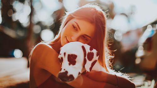 Free A young woman embraces her Dalmatian dog in a sunlit outdoor setting, exuding warmth and companionship. Stock Photo