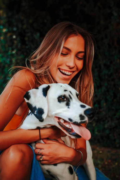 Free Smiling woman embracing a Dalmatian dog in an outdoor setting, showcasing happiness and companionship. Stock Photo