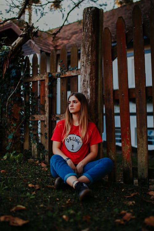 Woman Sitting next to Fence