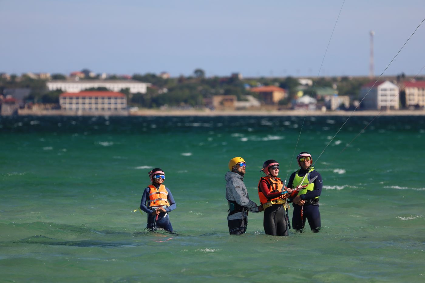 Students in helmets learning kitesurfing in shallow water