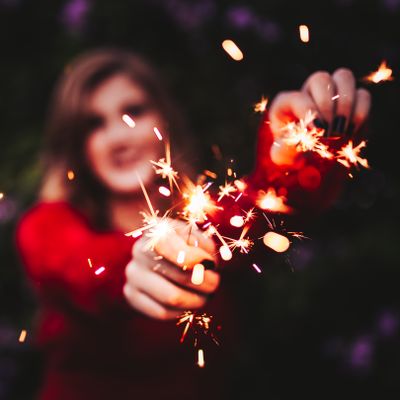 Woman holding glowing sparklers — photo by Matheus Bertelli on Pexels