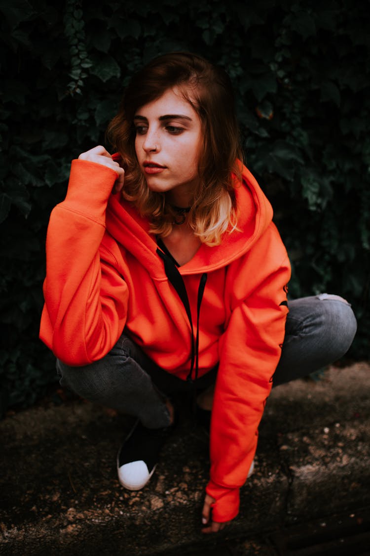 Teenage Girl Crouching In Orange Hoodie