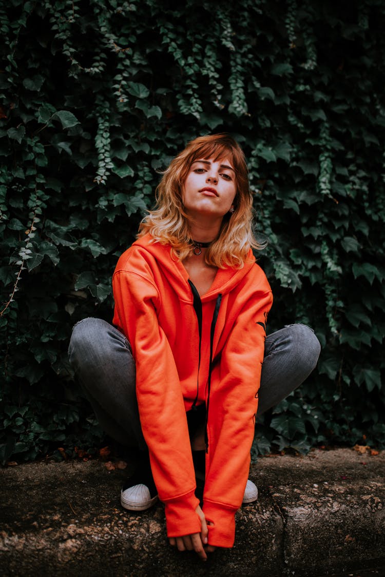 Crouching Woman Wearing Jeans And Orange Sweatshirt