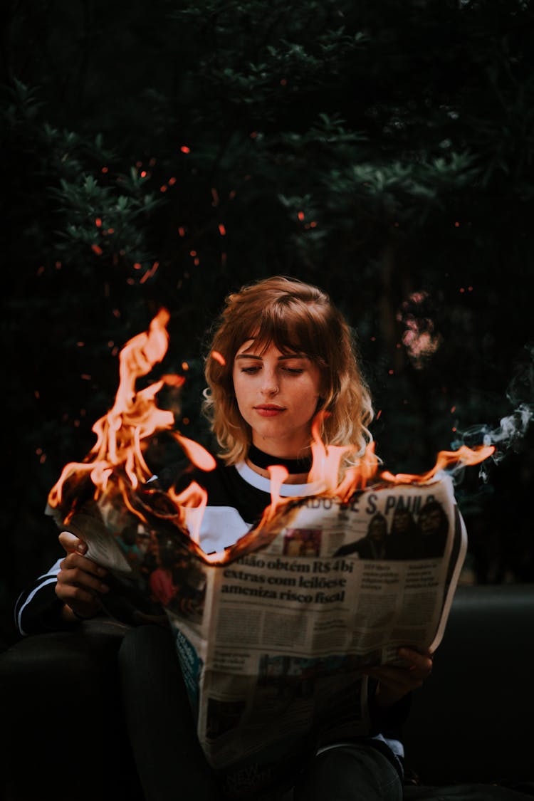 Young Woman Reading News From Burning Paper