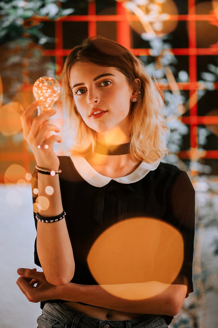 Nice Young Woman Holding Shiny Light Bulb In Hand