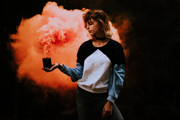 Young Woman In Sweatshirt Holding A Smoke Bomb