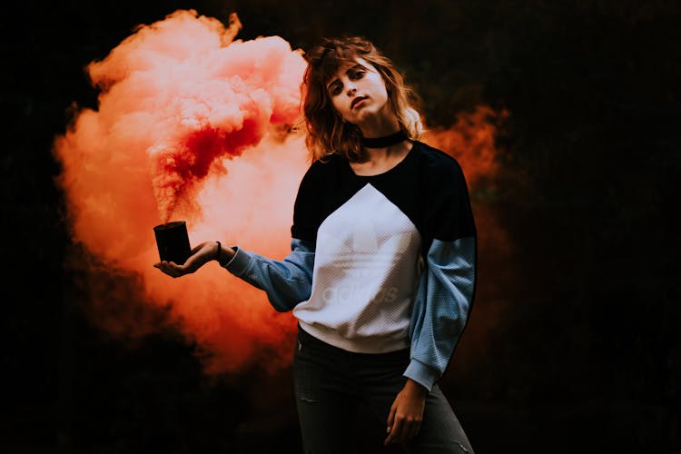 Young Woman In Sweatshirt Holding A Smoke Bomb 