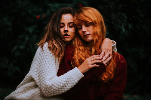 Redhead Woman and Woman With Her Face Painted Like a Deer Sitting Together 