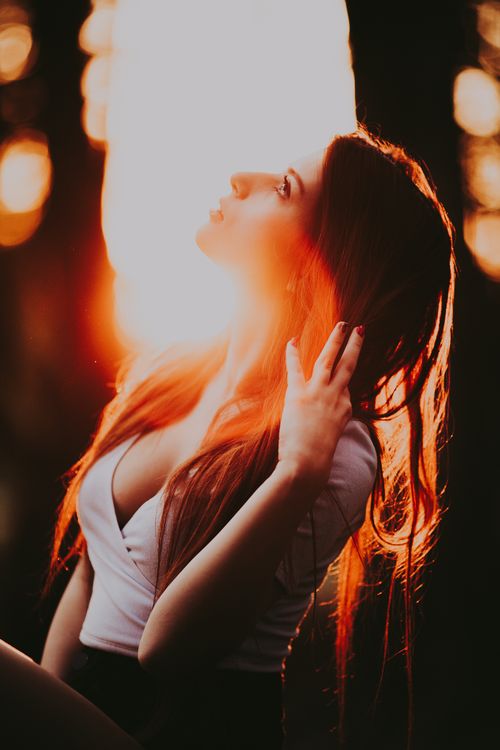Free Captivating portrait of a woman looking up, bathed in warm sunset light for serene and artistic mood. Stock Photo