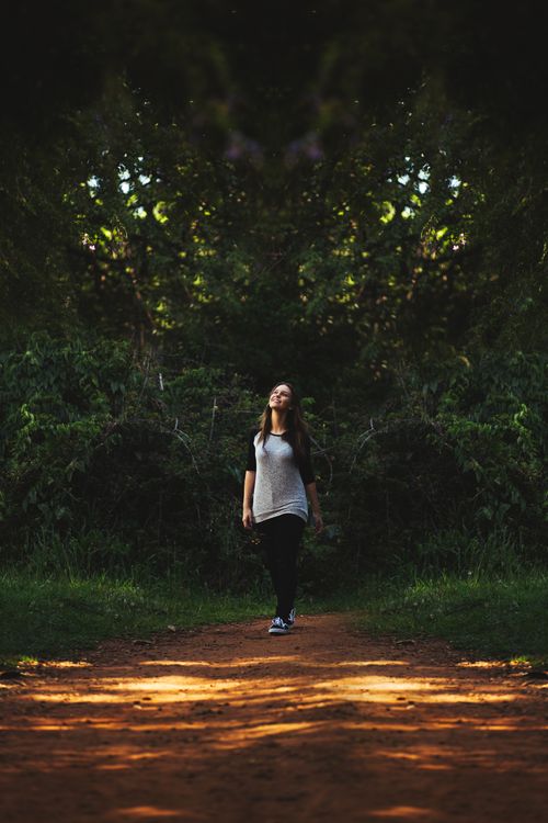 Free Young woman strolling on a serene forest path surrounded by lush greenery. Stock Photo