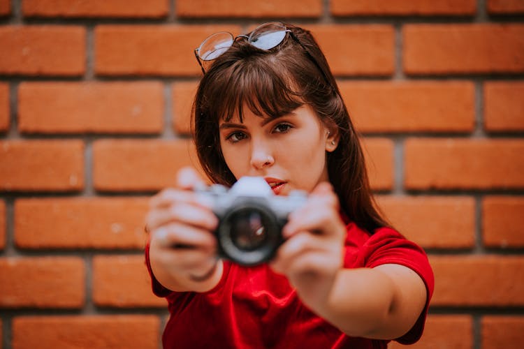 A Woman With Eyeglasses Holding A Camera