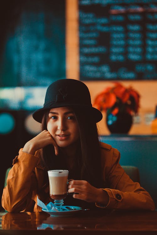 Girl Wearing a Black Hat Drinking Hot Chocolate in a Cafe