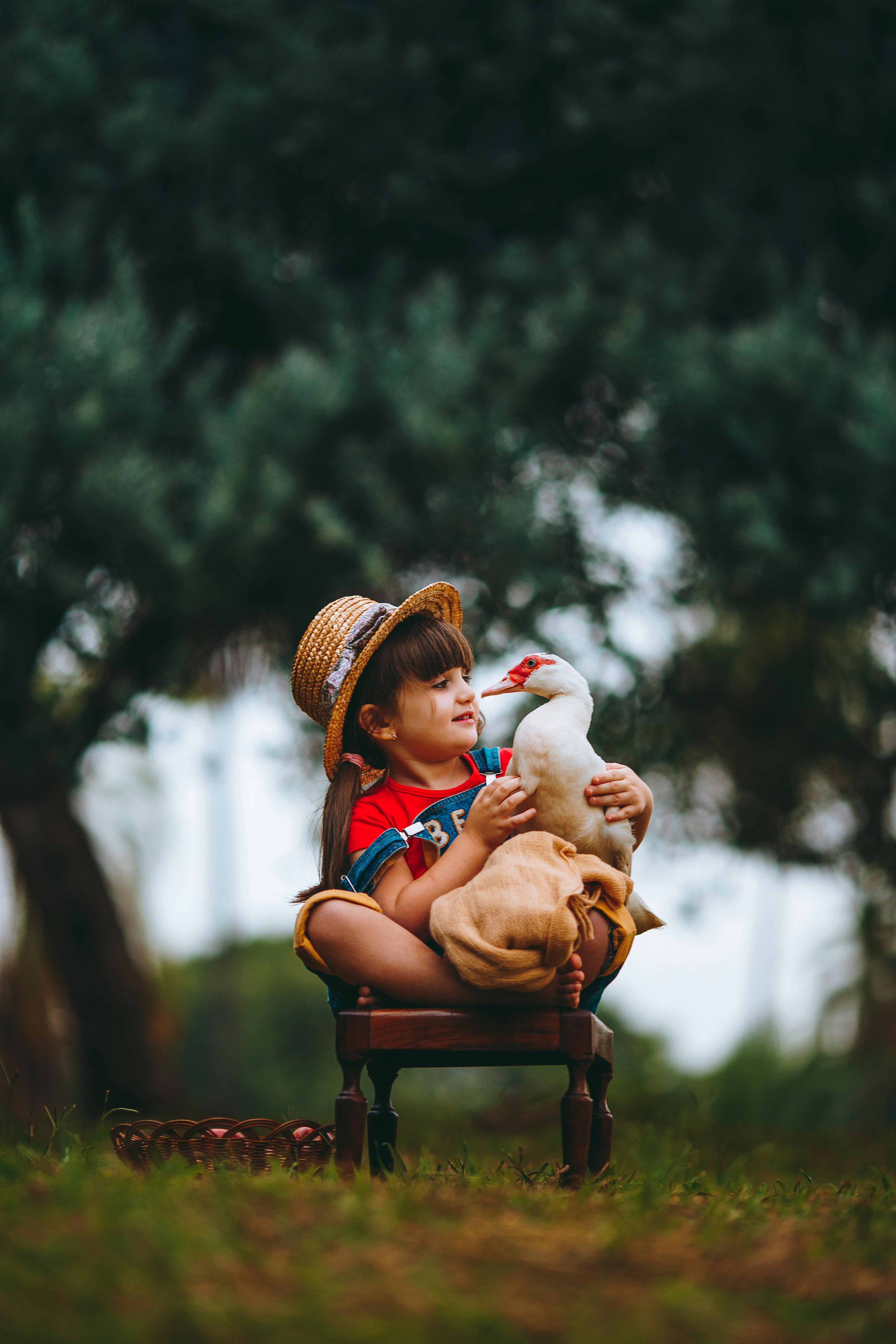Charming portrait of a child holding a duck outdoors, capturing friendship and playfulness.