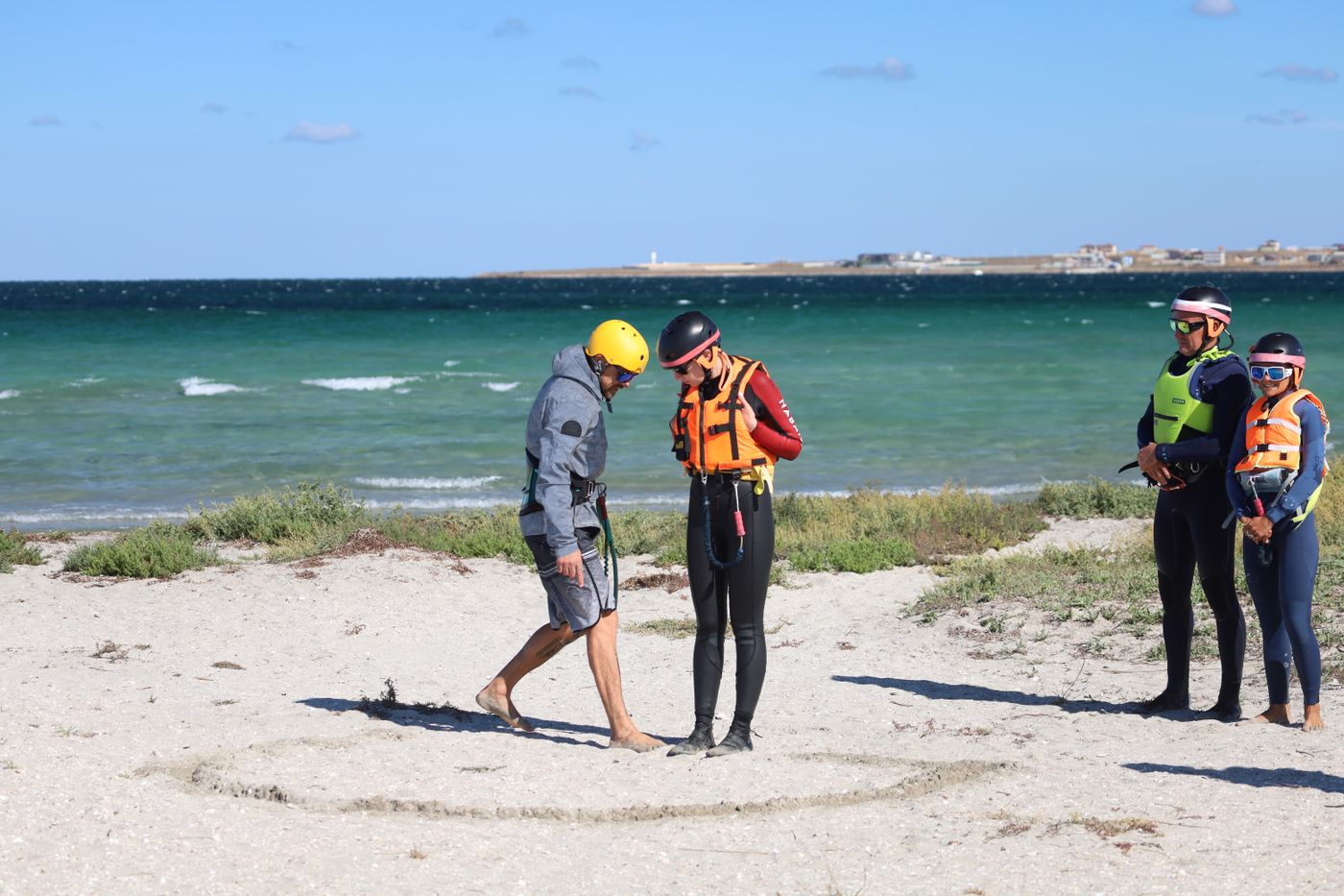 Water-sports group wearing helmets and safety equipment on a beach