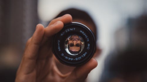 Hand Holding Lens with Man Face Reflection