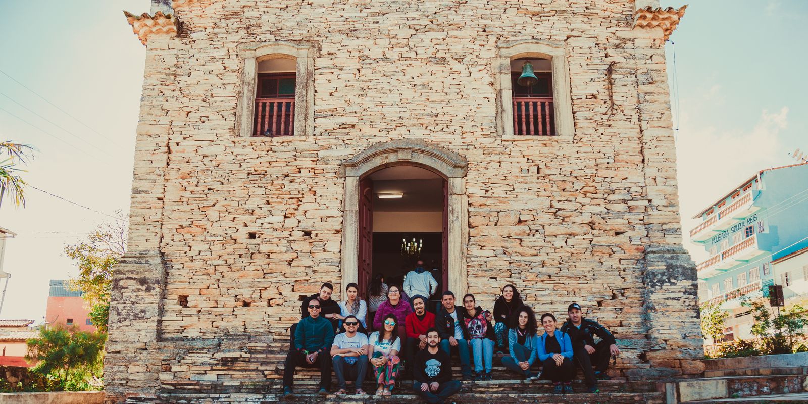A group of people sitting on steps outside a historic stone church, enjoying a sunny day - historic churches