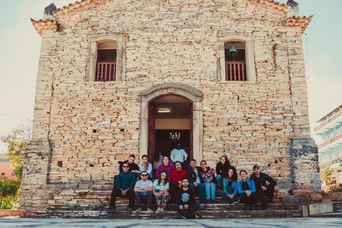 A group of people sitting on steps outside a historic stone church, enjoying a sunny day - historic churches